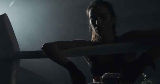 Vermoeide vrouwelijke bokser berust op de topes van de ring. Silhouet. Boksen concept — Stockvideo