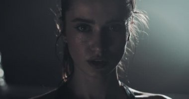 Boks halka üzerinde duran ve kameraya bakarak yorgun kadın boksör portresi