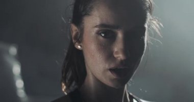 Boks halka üzerinde duran ve kameraya bakarak yorgun kadın boksör portresi