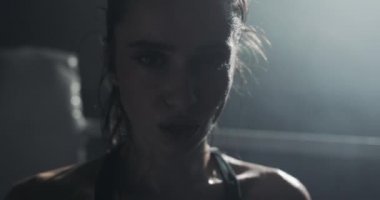 Boks halka üzerinde duran ve kameraya bakarak yorgun kadın boksör portresi