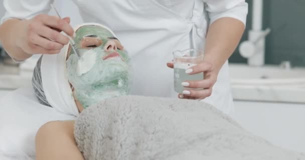 Mooie jonge meisje op de schoonheidsspecialiste doet de spa procedures. Vrouw is weggespoeld het groene gezichtsmasker — Stockvideo