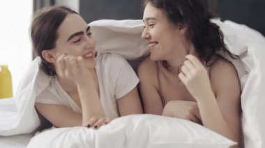 Mutlu lezbiyen çift evde battaniye altında yatakta birlikte yalan eğlenmek. LGBT lezbiyen çift birlikte. Yavaş hareket