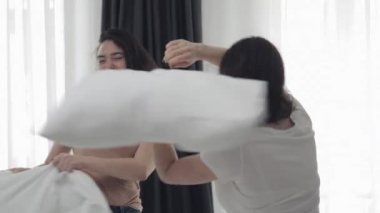 Mutlu lezbiyen çift yatakta yastık mücadele sahip, eğlenceli ve gülüyor. İnsanlar, romantik ilişki ve eğlence konsepti. Yavaş hareket