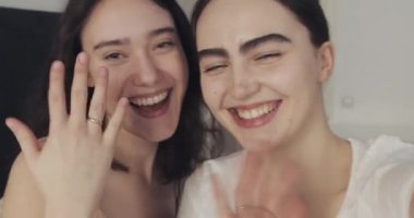 Mutlu lezbiyen çift video sohbet üzerinde smartphone. Onlar romantik kutlama zevk nişan yüzükleri gösteren. LGBT lezbiyen çift birlikte.