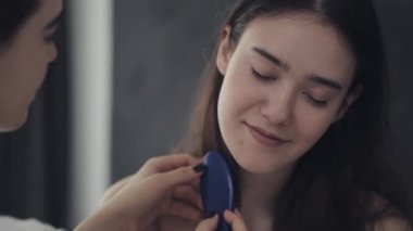 Lezbiyen kadın kız arkadaşı saç tarama. Mutlu lezbiyen çift evde yatakta oturuyor. Romantik ilişki konsepti. Yavaş çekim.