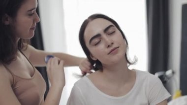 Lezbiyen kadın kız arkadaşı saç tarama. Mutlu lezbiyen çift evde yatakta oturuyor. Romantik ilişki konsepti. Yavaş çekim.