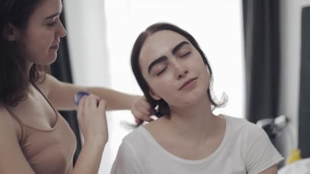 Mulher lésbica pentear o cabelo sua namorada. Casal lésbico feliz sentado na cama em casa. Conceito de relacionamento romântico. Movimento lento . — Vídeo de Stock