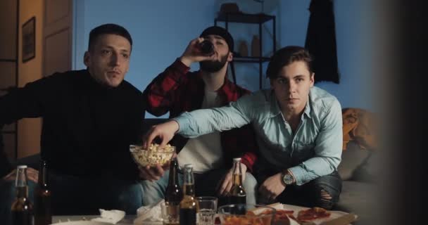 Tres amigos viendo el partido de fútbol en casa, animando al mejor equipo de fútbol. Emoción. Los fans de los hombres celebran ganar . — Vídeos de Stock