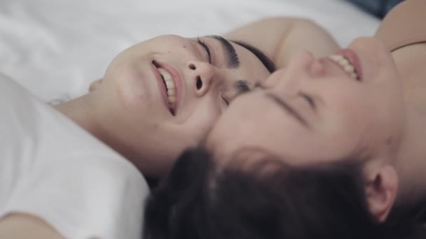Lyckliga lesbiska tjejer ligger på sängen och ler och njuter av varandra. HBT-familjens koncept, slow motion. — Stockvideo