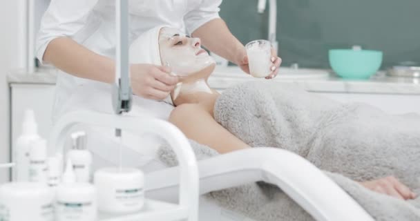 Schoonheidsspecialist zet een wit masker op gezicht patiënt in Spa Salon. Concept van lichaamsverzorging gezonde levensstijl — Stockvideo