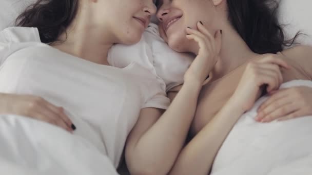 Couple lesbien étreignant et souriant tout en étant couché ensemble dans le lit à la maison. Jeunes lesbiennes baisers et câlins après le réveil — Video