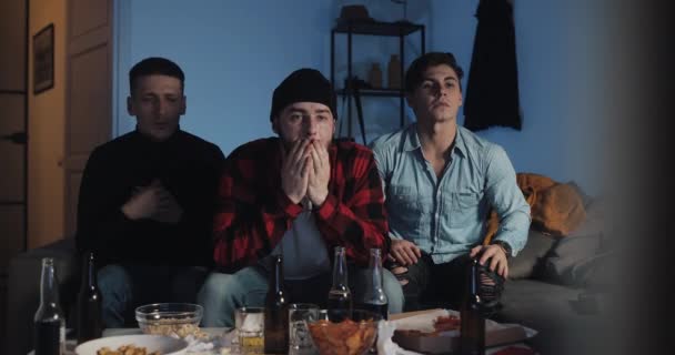 Tres amigos viendo el partido de fútbol en la televisión en casa, decepcionados equipo . — Vídeos de Stock