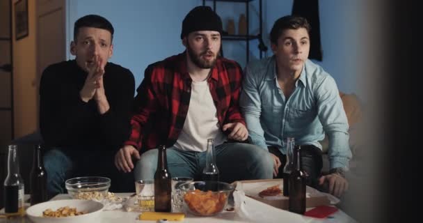 Tres amigos viendo el partido de fútbol en la televisión en casa, decepcionados equipo . — Vídeos de Stock