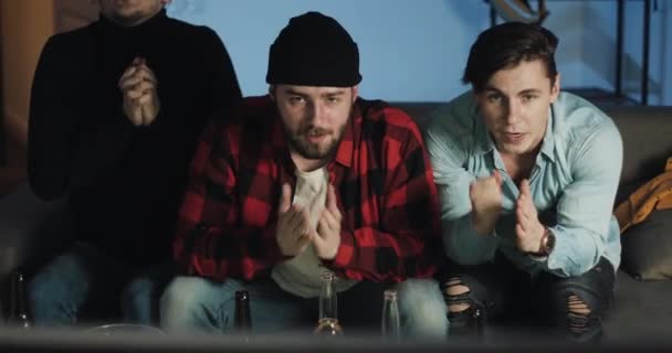 Tres amigos viendo el partido de fútbol en casa, animando al mejor equipo de fútbol. Emoción. Los fans de los hombres celebran ganar . — Vídeos de Stock