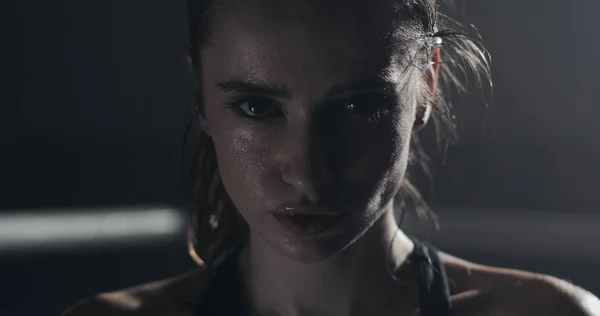 Boks halka üzerinde duran ve kameraya bakarak yorgun kadın boksör portresi