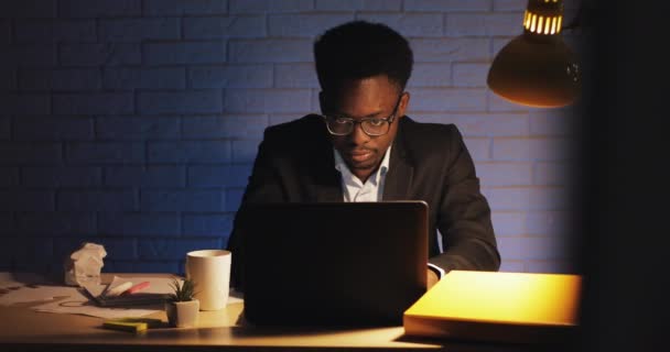 Trabajador de oficina cansado trabajando en el portátil a altas horas de la noche. Está bostezando y bebiendo café. Un hombre de negocios está solo en la oficina. Workaholic, el concepto de plazo . — Vídeos de Stock