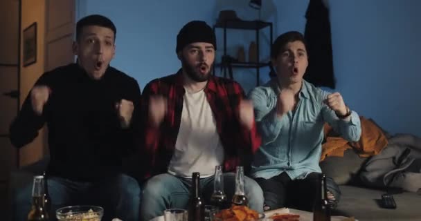 Tres amigos viendo el partido de fútbol en casa, fanáticos del fútbol apoyando a su equipo — Vídeos de Stock