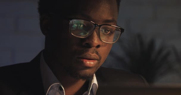 Набридло працювати на комп'ютері молодий чорний чоловік штовхає свої окуляри і Потирає очі. Трудоголік, докладаємо всіх зусиль. Нічний час. Крупним планом. — стокове відео