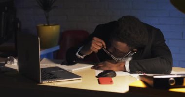 Yorgun Afro-Amerikan erkek ofis çalışanı gece geç saatlerde ofiste onun bilgisayar masasında uyku sonra uyanma ve çalışmaya devam.