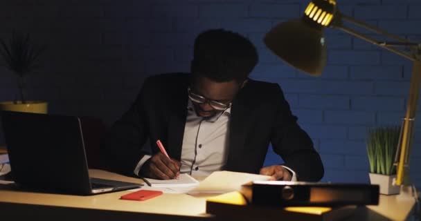Ung affärsman med bärbar dator och papper som jobbar sent på kvällskontoret. Företag, arbetsnarkoman, deadline koncept. — Stockvideo