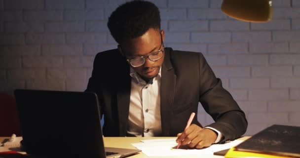 Empresário cansado com computador portátil e documentos a trabalhar no escritório nocturno. Ele assina os documentos. Workaholic, conceito de prazo. Empresário estressado com dor de cabeça trabalhando até tarde em seu escritório . — Vídeo de Stock