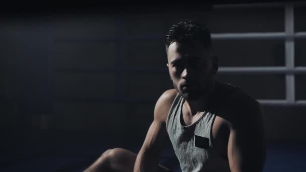 Retrato de boxeador cansado sentado en el ring de boxeo y descansando después de un duro entrenamiento. Hombre mirando a la cámara . — Vídeo de stock