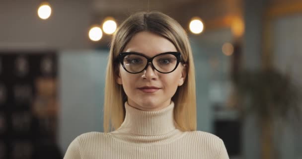 Portrét mladé úspěšné ženy oblečené ve stylových brýlích na kameru stojící v pracovní ploše. — Stock video