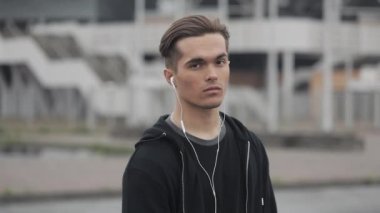 Stadyum arka planda çalışan kulaklıklar ile çekici erkek Runner portresi. Atlet kafasını çevirir ve kameraya bakıyor. Sağlıklı Fitness atletik adam jogging açık havada.