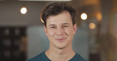 Modern ofiste duran genç gülümseyen başarılı işadamıportresi. Yakın çekim.