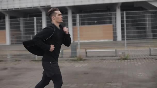 Atractivo joven corriendo al aire libre en cámara lenta. Clima lluvioso. Entrenamiento de ejercicio cardiovascular. Estilo de vida saludable - correr . — Vídeos de Stock