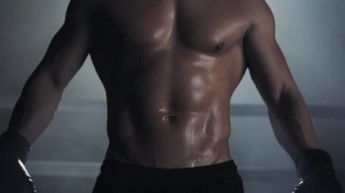 Bir erkek boksör bir basın ve kaslar gösterir. Kapat şunu. Boks yüzüğü arka planı. Kamera üzerinde poz çıplak atlet.