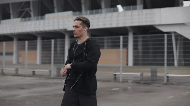 Atractivo atleta masculino hace ejercicio de la mañana al aire libre cerca de cámara lenta en el clima nublado. Entrenamiento de pie en la calle cerca del estadio deportivo. Estilo de vida saludable voluntad poder motivación concepto . — Vídeo de stock