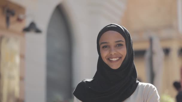 Πορτρέτο της νεαρής όμορφη μουσουλμανική γυναίκα φορώντας μαντίλα μαντίλας γελώντας χαρούμενα στην παλιά πόλη. Κοντινό. — Αρχείο Βίντεο