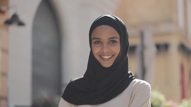 Πορτρέτο της νεαρής όμορφη μουσουλμανική γυναίκα φορώντας μαντίλα μαντίλας γελώντας χαρούμενα στην παλιά πόλη. Κοντινό. — Αρχείο Βίντεο