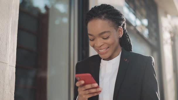 Empresária afro elegante enviando mensagem de voz de áudio no celular ao ar livre conversando com assistente móvel. Senhora de negócios com dreadlock usando o reconhecimento de voz do smartphone — Vídeo de Stock
