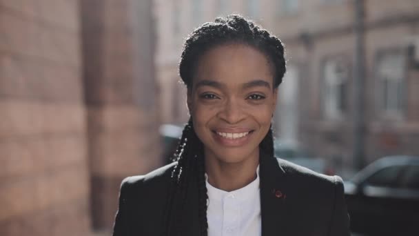 Retrato de mulher de negócios afro-americana elegante que está perto do centro de bisbilhotice. Ela olha para a câmara e sorri. Black Stylish. Dreadlocks. Penteado Afro . — Vídeo de Stock