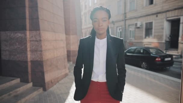 Retrato de una mujer de negocios afro con estilo de pie cerca del centro de negocios. Está mirando a la cámara. Negro con estilo. Ricitos. Peinado afro . — Vídeos de Stock