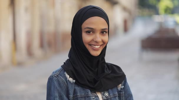 Портрет красивой молодой мусульманки в хиджабе, улыбающейся в камеру, стоящую на фоне старого города . — стоковое видео