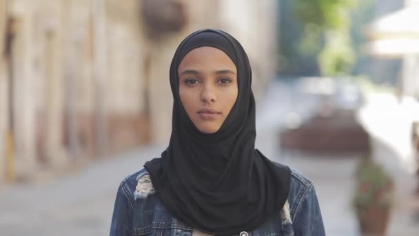 Portret van mooie jonge moslim vrouw het dragen van hijab hoofddoek glimlachend in de camera staande op de oude stad achtergrond. — Stockvideo