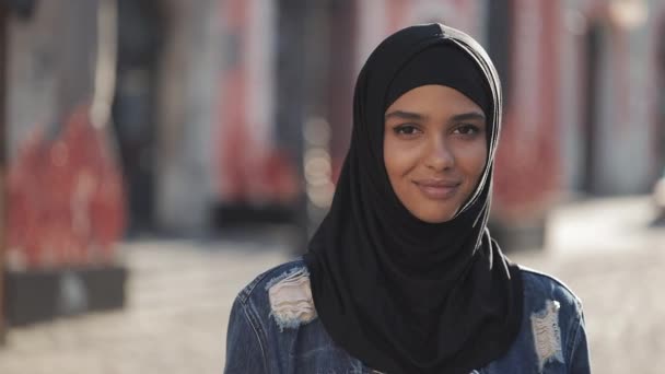 Ritratto di bella giovane donna musulmana che indossa hijab velo sorridente nella macchina fotografica in piedi sul vecchio sfondo della città . — Video Stock