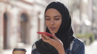 Genç Müslüman kadın cep telefonda sesli mesaj gönderme açık mobil asistan konuşurken. Kız akıllı telefon ses tanıma kullanarak, düşünceler, Sesli çevirme mesajı dikte
