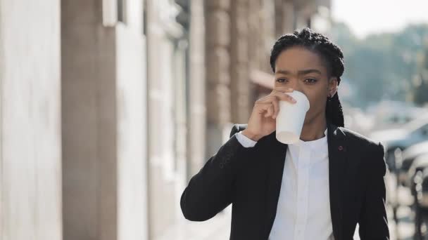 Portret van een serieuze Afro-Amerikaanse zakenvrouw in een pak, wandelen door de stad, en koffie drinken. Concept: nieuwe Business, werkdag, freelancer. — Stockvideo