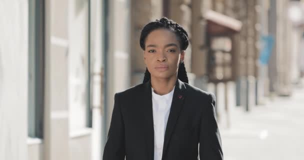 Porträtt av allvarliga afroamerikansk affärskvinna stående på den gamla gatan och passerar händerna. Hon tittar på kameran och ler. Svart snygg. Dreadlocks. Afro frisyr. — Stockvideo