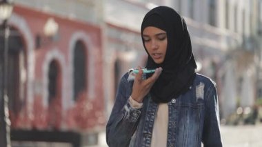 Genç Müslüman kadın cep telefonda sesli mesaj gönderme açık mobil asistan konuşurken. Kız akıllı telefon ses tanıma kullanarak, düşünceler, Sesli çevirme mesajı dikte