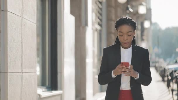 Attraente donna d'affari che utilizza smartphone a piedi per strada vicino al centro business. Black Stylish. Serrature . — Video Stock