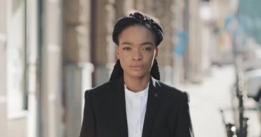 Ciddi Afro-Amerikan iş kadını eski sokak arka planda duruyor. Kameraya bakıyor ve gülümsüyor. Siyah Şık. Dreadlocks. Afro Saç Modeli.