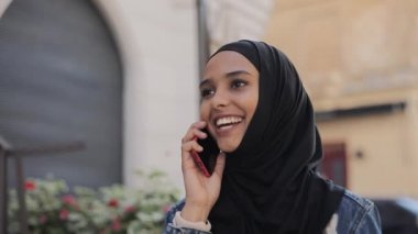 Başörtüsü başörtüsü takan güzel genç Müslüman kadın eski şehir merkezine gider ve telefonda konuşur.