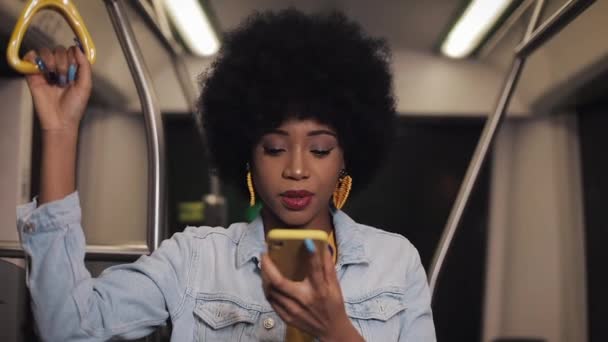 Молода афроамериканець жінка за допомогою смарт-телефону розпізнавання голосу, диктує думки, голосовий набір повідомлення їзда на громадському транспорті. — стокове відео