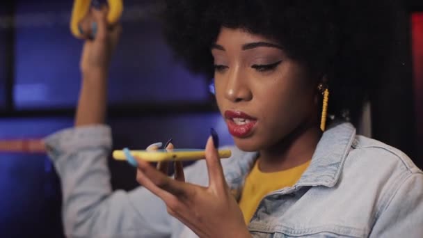 Fiatal afroamerikai nő segítségével okos telefon hang felismerés, diktálja gondolatait, hangtárcsázás üzenet lovaglás a tömegközlekedési. — Stock videók
