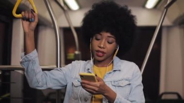 Müzik dinleyerek, şarkı söylemek ve toplu taşıma da komik dans kulaklık ile i giyen genç Afrikalı-Amerikalı kadın portresi. Tırabı tutuyor..